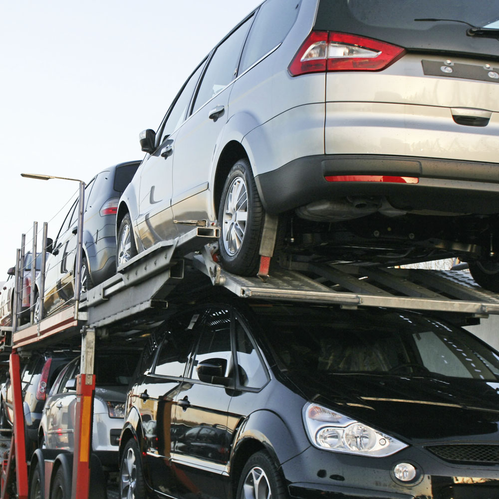 grupo de autos nuevos siendo transportados sin rodar sobre madrina nodriza color rojo